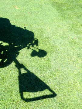 Shadow Of A Push Cart Filled With Golf Clubs