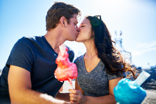 couple kissing on romantic date with cotton candy on sunny summer day