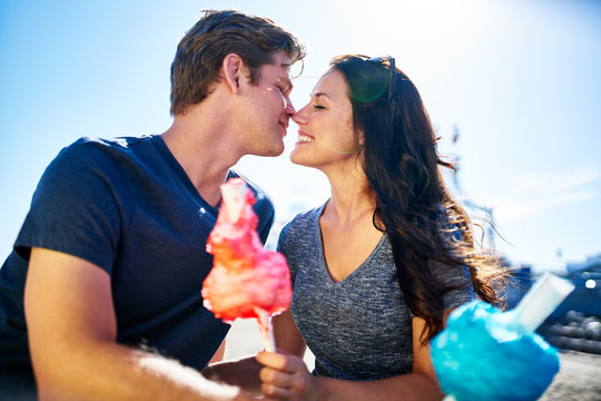 romantic couple about to kiss on date with cotton candy on sunny summer day