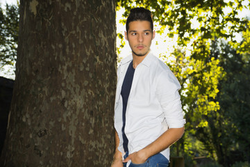 Attractive young man in park next to trees