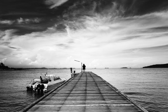 Fototapeta Woman alone on bridge to the ocean black and white style