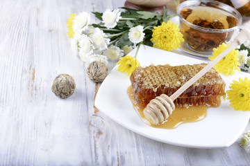 concept of honeycombs and flowers on white wooden background