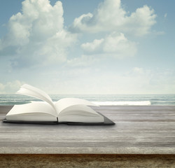 Open book on table in front of sea and sky summer background
