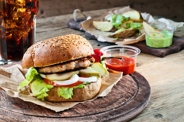 Fresh burger with sauce and potatoes on a rustic