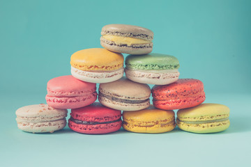 Pile of colorful macaroons stacked up like a tower in blue turquoise pastel isolated background - in vintage tone