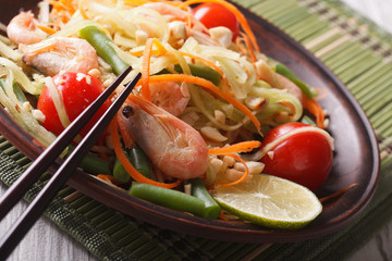 papaya salad som tam with shrimp on a plate. macro, horizontal

