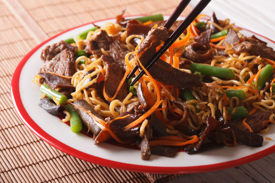 Lo mein noodles with beef and black fungus macro on a plate. Horizontal
