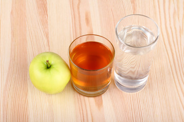 Apple juice in a glass, the glass of water and Apple on wooden background