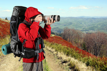 tourist in a red jacket with a gray backpack taking pictures