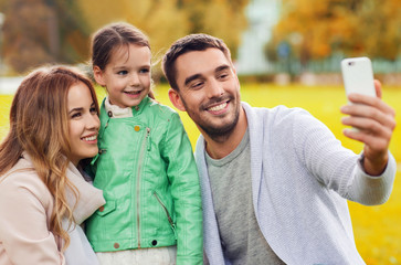 Fototapeta premium happy family taking selfie by smartphone outdoors