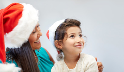 happy mother and little girl in santa hats at home