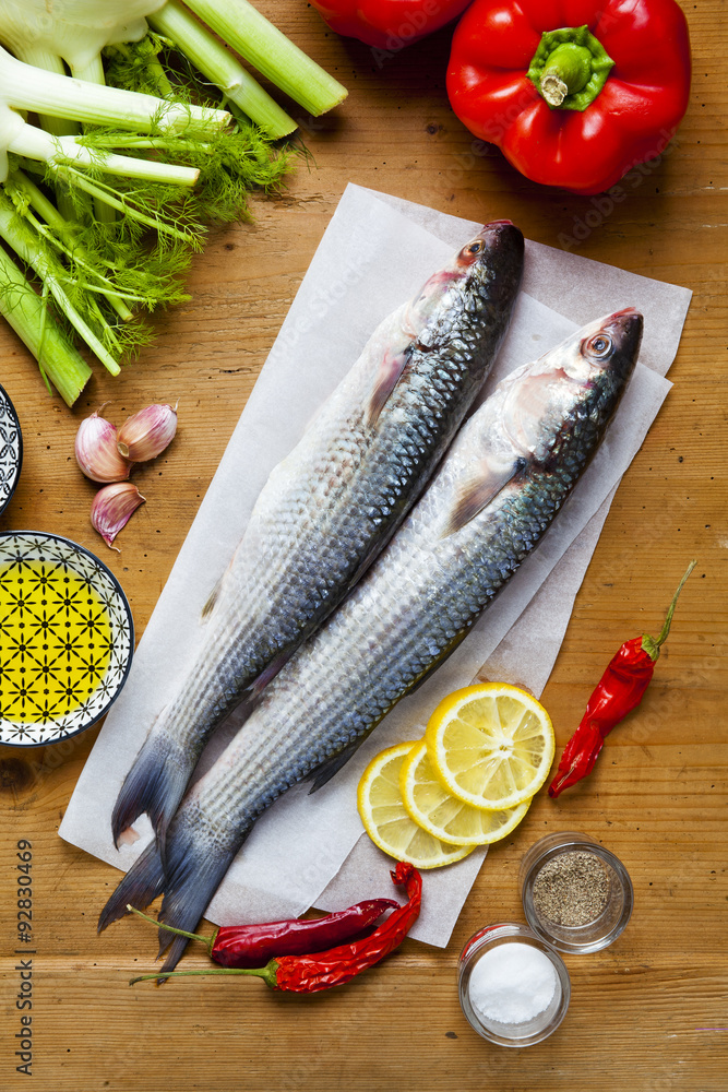 Wall mural raw fresh fish with vegetable ingredients on a wooden texture ta