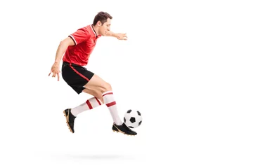 Gordijnen Young athlete jumping and kicking a football © Ljupco Smokovski