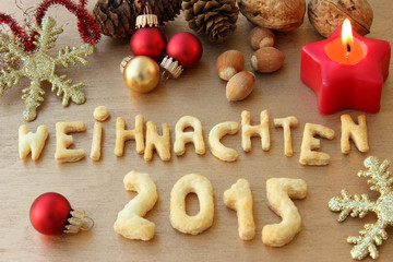 Fototapeta premium Weihnachten 2015 in Schrift mit Tannenzapfen, Weihnachtskerze, Weihnachtskugeln und Nüssen 