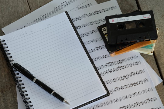concept song composer: song notes, tape cassette, notebook and pen on wooden background