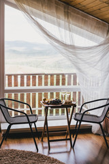Table with wine, cheese, bread, grapes and pears standing on a cozy balcony