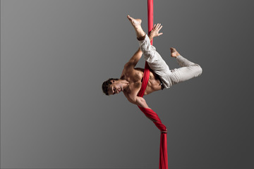 Sporty young man doing exercise with elastics, aerial silk ribbons, aerial. Sport training gym and...