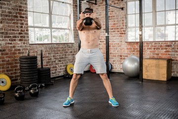 Shirtless man lifting kettlebell