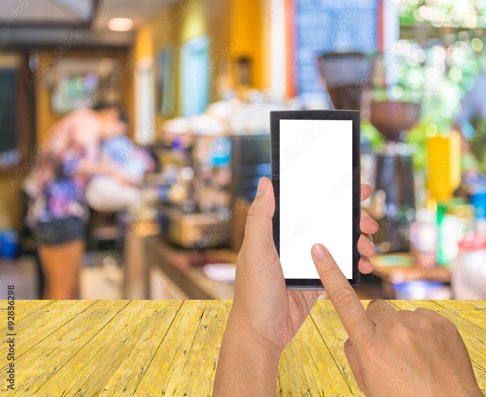 Wall mural male hand is holding a modern touch screen phone and Coffee shop