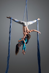 Sporty couple doing exercise with elastics, aerial silk. Sport training gym and lifestyle concept. Anti-gravity yoga.