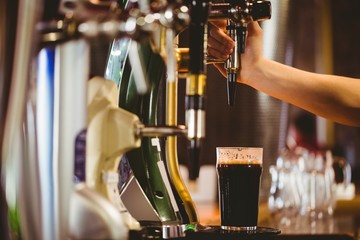 Cropped hand of bartender dispensing beer