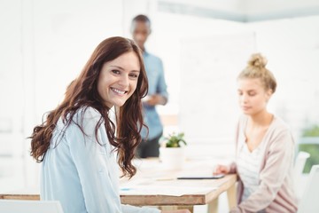 Portrait of smiling woman while sitting at desk