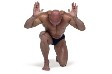 Muscular man bending on knee with arms raised