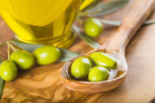 Aceite de oliva virgen extra y aceitunas verdes en una cuchara de madera comida saludable