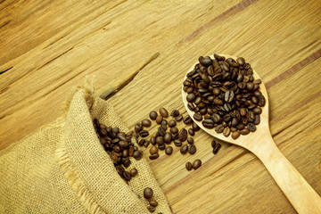 Coffee beans spilling from a burlap bag and a scoop on a texture