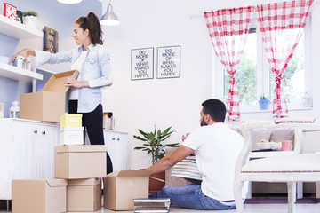 Portrait of a smiling couple packing boxes in a new house