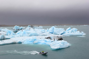 Motorboot vor blauen Eisbergen auf dem See Jökulsarlon auf Island