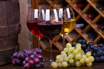Red, rose and white glasses with grape on old wooden barrel
