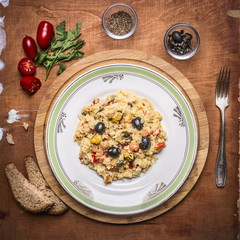 cooked paella with seafood dish on a chopping board with bread seasoned with herbs and tomatoes with a fork on rustic wooden background top view