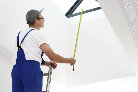 Mężczyzna w stroju roboczym pracuje przy montażu okien dachowych