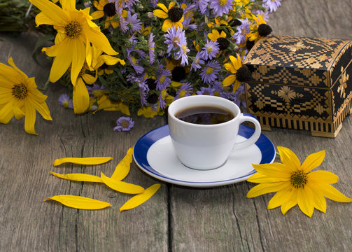 cup of coffee, casket, flower, petals and wild flowers on an old