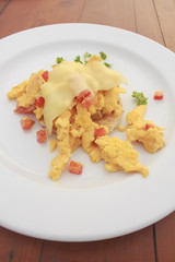 Scrambled egg with cheese and pancake in white dish on wooden table
