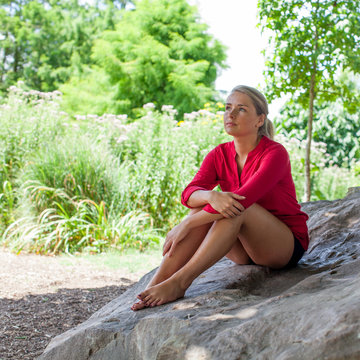 gloomy young woman sitting on giant stone for summer freshness