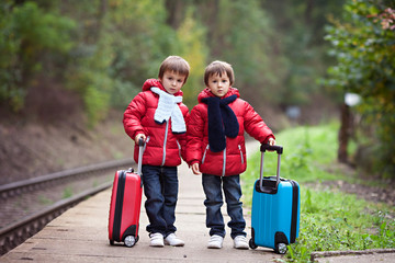 Two boys on a railway station, waiting for the train with suitca