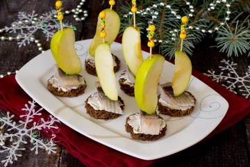 Deurstickers Appetizer canape with herring, apples on a dark wooden backgroun © elena_hramowa