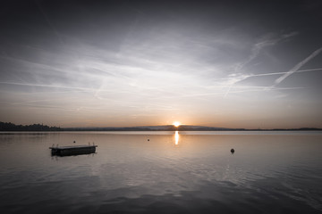 Fototapeta premium Sunset on the lake. Magnificent colors of the sky reflected in the water. Board for diving. Toning.