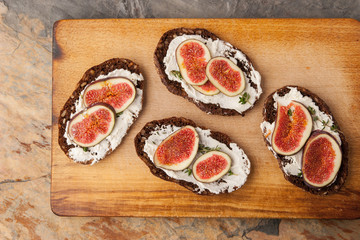 Bread with ricotta  , fig and thyme on the wooden board top view