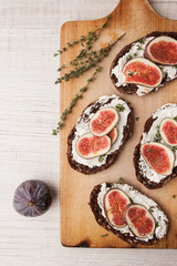 Bread with fresh cheese, fig and sprig on thyme on the wooden board  vertical