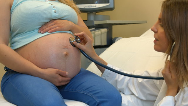 Doctor using a stethoscope on a pregnant womans stomach