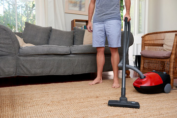 man at home vacuuming the carpets