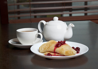 teapot, cup of tea and pancakes with cherry confiture