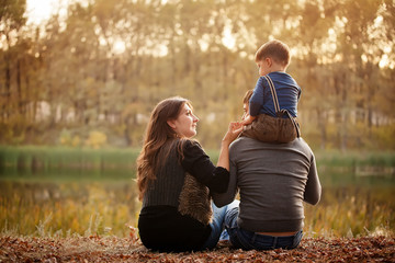 Family in autumn forest, view from the back