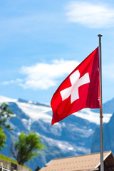 Swiss flag against Alps mountains