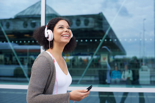 Smiling young woman walking with cellphone and headphones