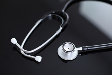 Stethoscope on black, reflective background