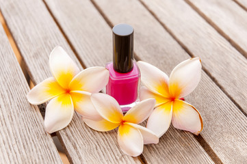 Obraz na płótnie Canvas Fuchsia nail polish in the bottle and flowers on the woody background